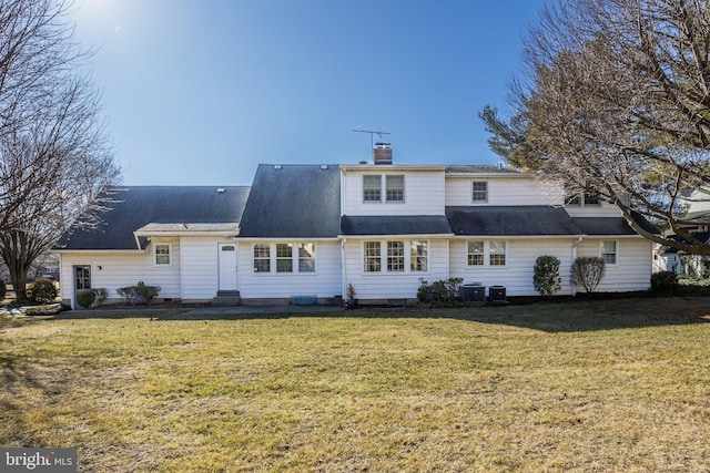 back of house with central air condition unit, a chimney, and a lawn