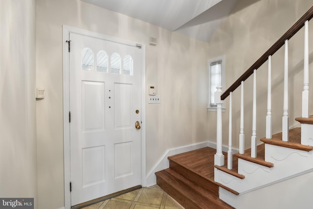 foyer featuring stairs and baseboards