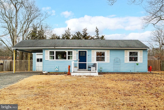 ranch-style house featuring driveway, an attached carport, and fence