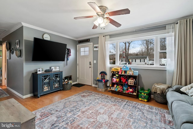 living room featuring ceiling fan, baseboards, crown molding, and wood finished floors