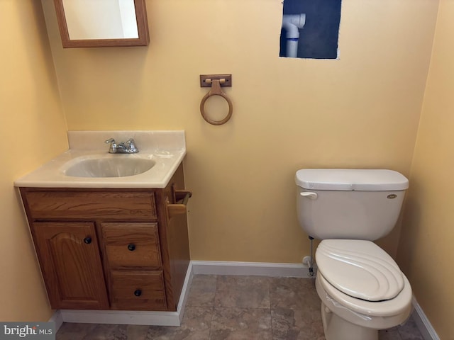 half bathroom with toilet, baseboards, and vanity