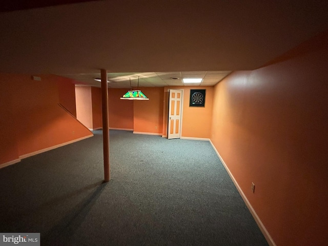 finished below grade area with baseboards, a drop ceiling, and carpet flooring