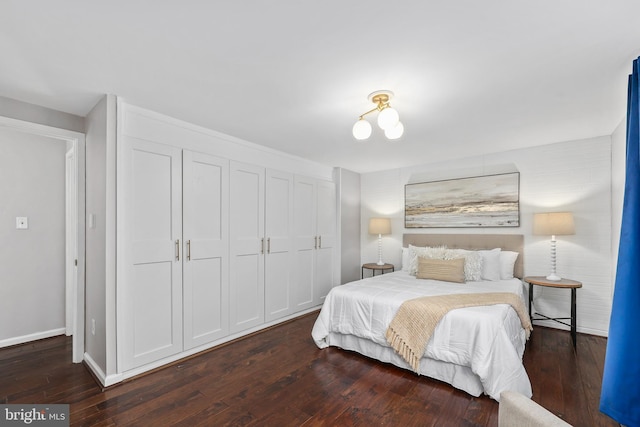 bedroom with dark wood-type flooring, a closet, and baseboards