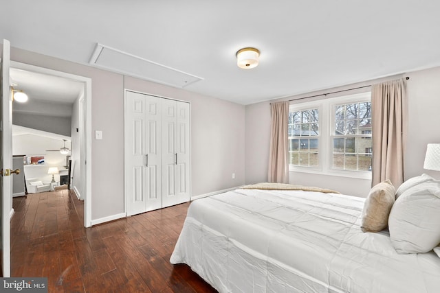 bedroom featuring attic access, baseboards, dark wood finished floors, and a closet