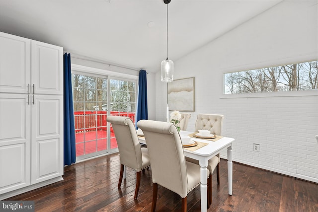 dining room with lofted ceiling, brick wall, and dark wood-type flooring