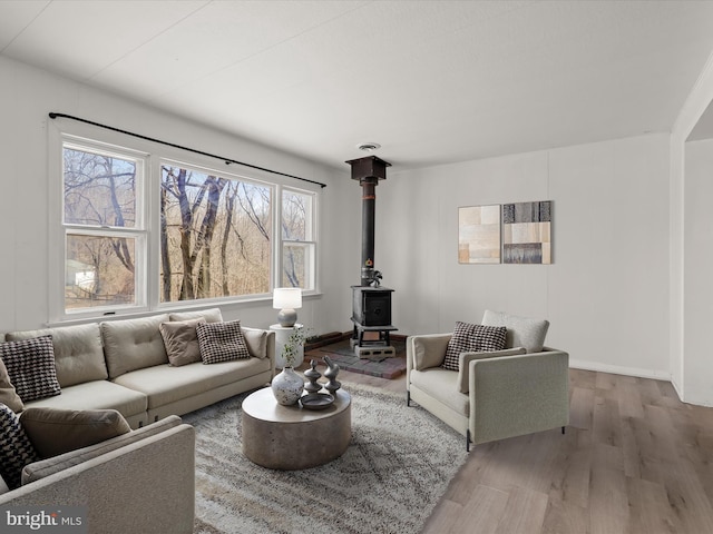 living area featuring baseboards, wood finished floors, and a wood stove