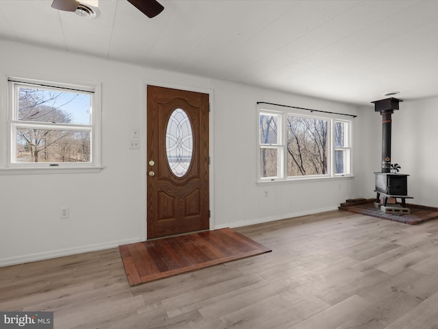 entryway with a healthy amount of sunlight, a wood stove, and wood finished floors