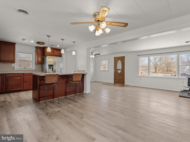 kitchen featuring visible vents, a breakfast bar, light wood-style flooring, light countertops, and stainless steel fridge