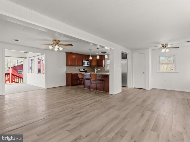 living room with light wood-style floors, a healthy amount of sunlight, and a ceiling fan