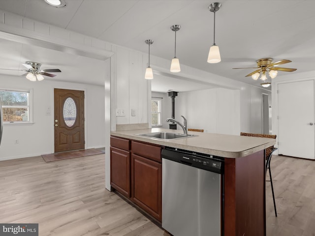 kitchen with a breakfast bar area, light wood-style flooring, a sink, light countertops, and dishwasher