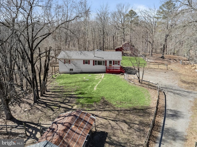 view of front of property with dirt driveway, fence, a front yard, a shingled roof, and crawl space