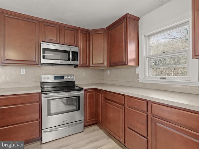 kitchen featuring light countertops, brown cabinetry, light wood-type flooring, and stainless steel appliances