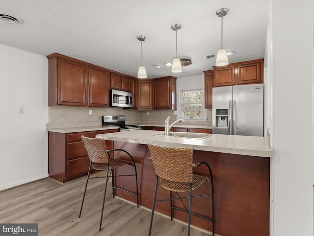 kitchen with visible vents, light wood-style flooring, a sink, appliances with stainless steel finishes, and light countertops