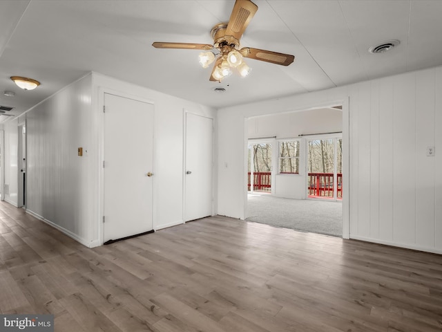 interior space featuring wood finished floors, visible vents, two closets, and ceiling fan