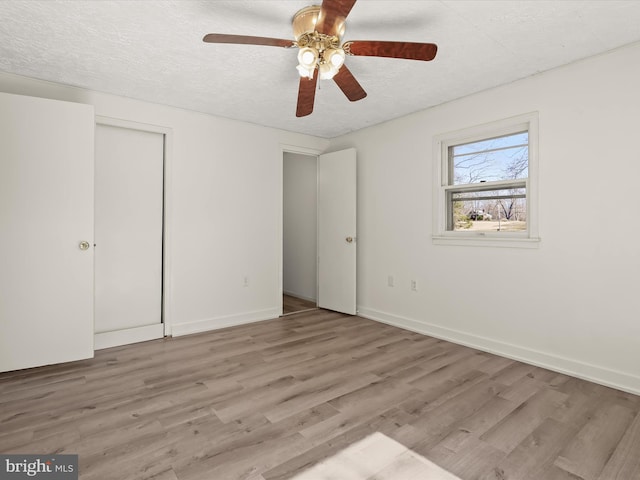 unfurnished bedroom featuring baseboards, light wood-type flooring, and a textured ceiling