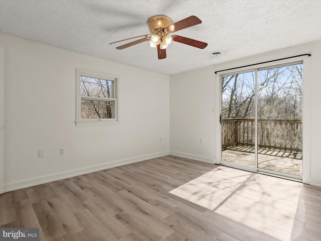 empty room with visible vents, a textured ceiling, baseboards, and wood finished floors