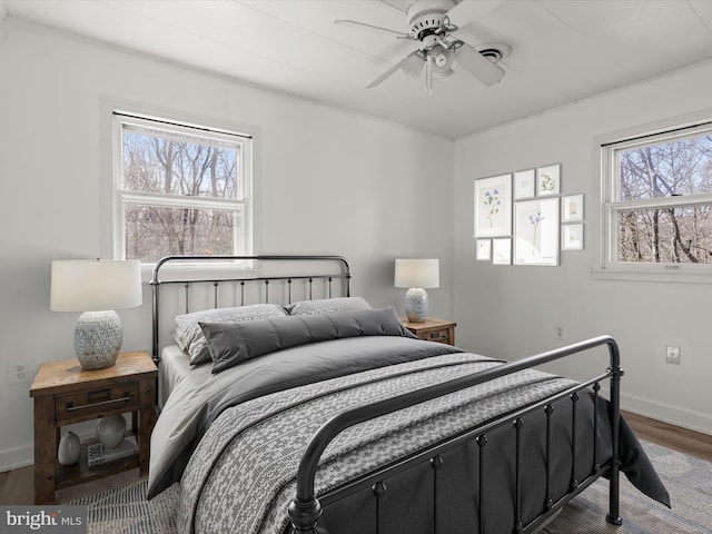 bedroom with multiple windows, baseboards, and wood finished floors