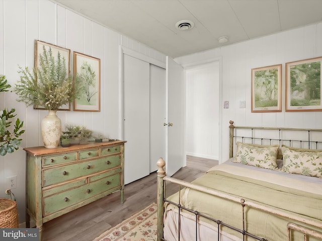 bedroom featuring visible vents, a closet, and wood finished floors