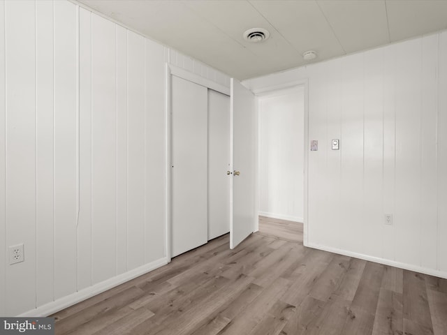 unfurnished bedroom featuring a closet, visible vents, baseboards, and wood finished floors