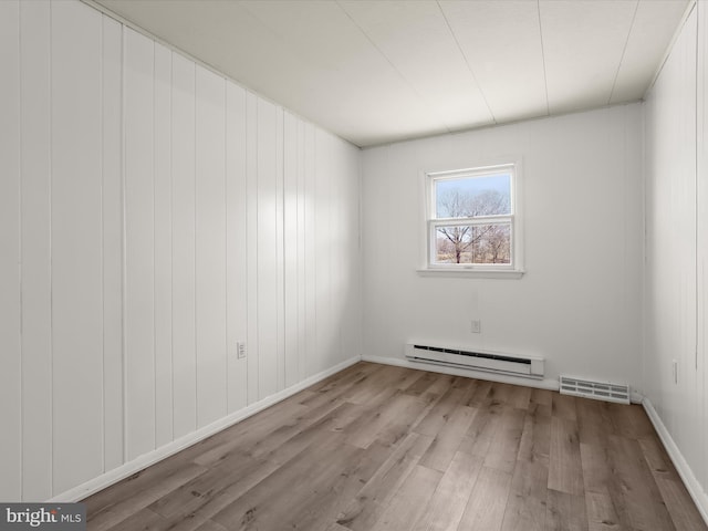 unfurnished room featuring baseboard heating, visible vents, and wood finished floors