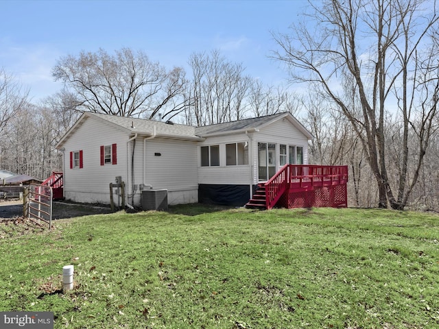 exterior space with cooling unit, a wooden deck, a front lawn, and a sunroom