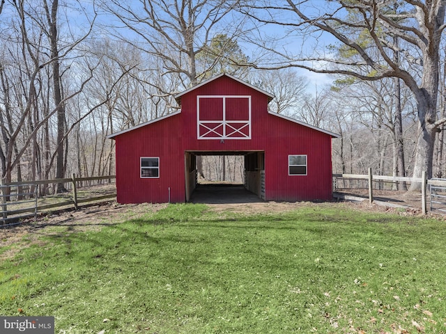 view of barn with fence and a lawn