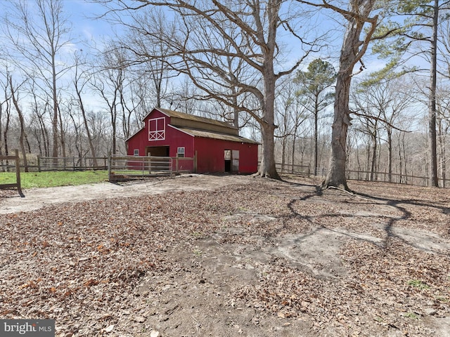 view of barn featuring fence and driveway