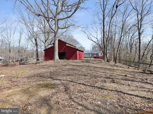 view of yard with a barn, an outdoor structure, and fence