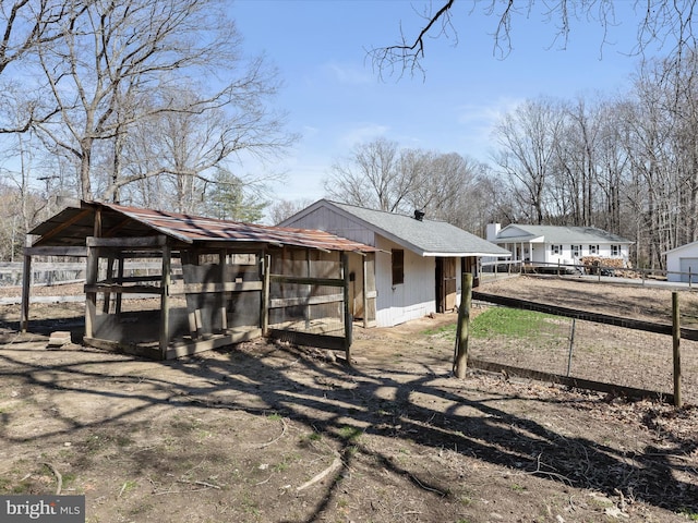 view of property exterior featuring roof with shingles, an outdoor structure, exterior structure, and fence