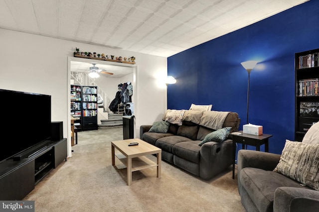 living room featuring stairs, a ceiling fan, and light colored carpet