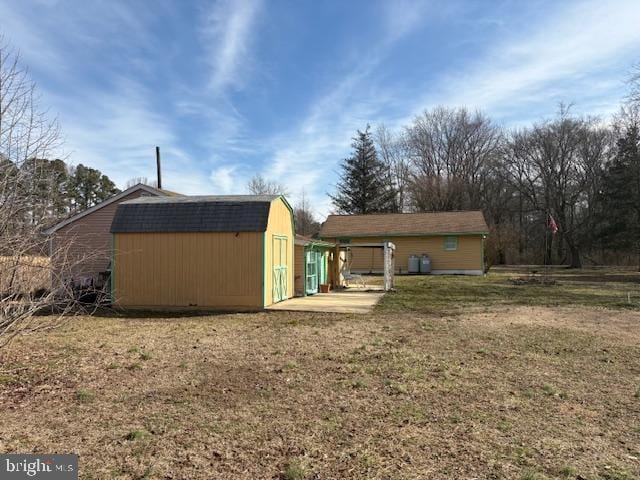 back of house featuring a yard, an outdoor structure, and a storage shed