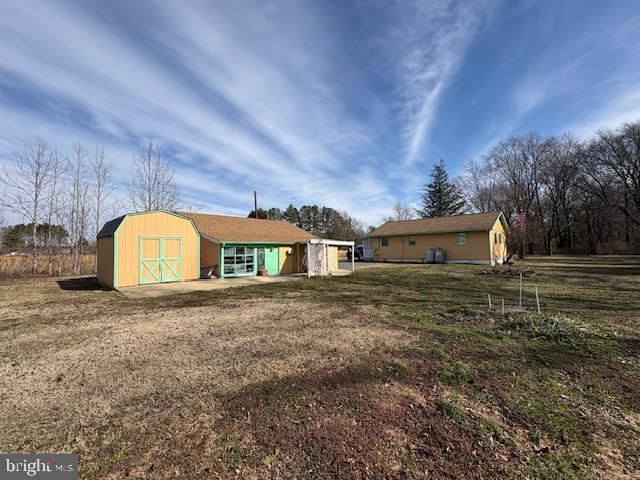 back of property with an outbuilding, a yard, and a storage shed