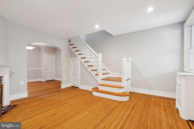 staircase with arched walkways, recessed lighting, baseboards, and wood finished floors