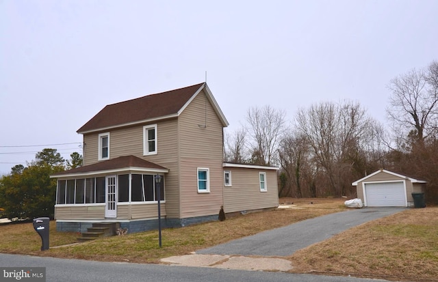 view of home's exterior featuring aphalt driveway, a garage, an outdoor structure, a sunroom, and a yard