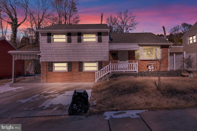 split level home with driveway, a shingled roof, and brick siding