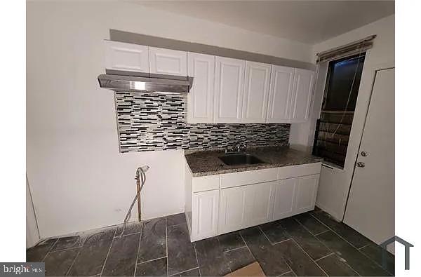 kitchen featuring decorative backsplash, white cabinets, a sink, and wood finish floors