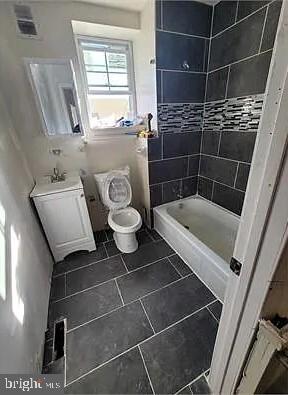 bathroom featuring tiled shower, vanity, and toilet