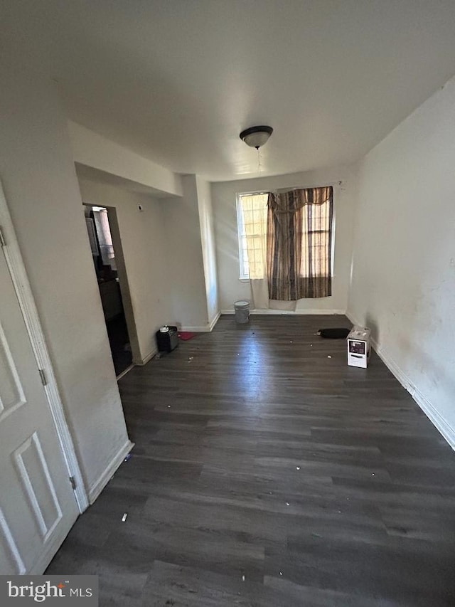 empty room featuring dark wood-type flooring and baseboards