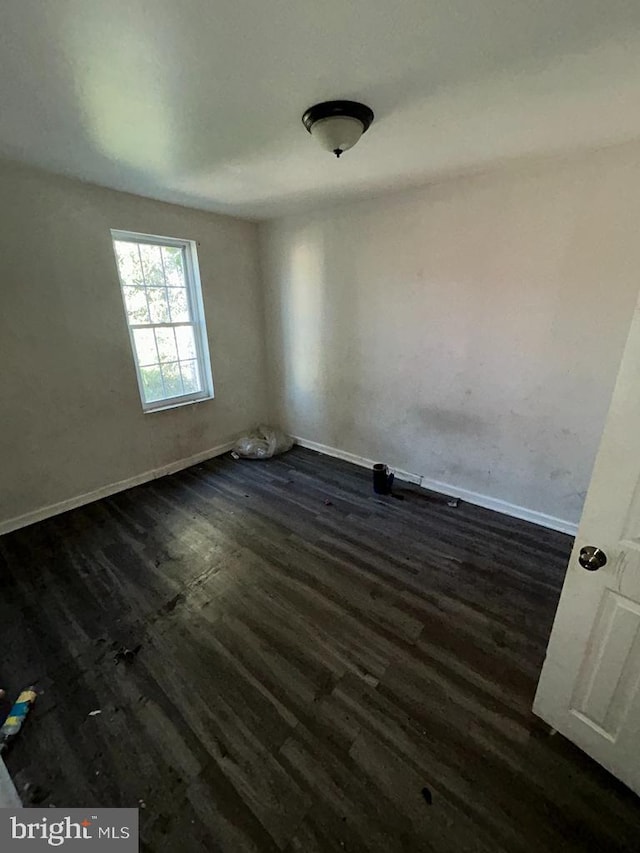 unfurnished room with baseboards and dark wood-style flooring