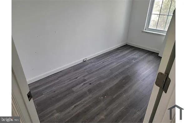 empty room featuring dark wood finished floors and baseboards