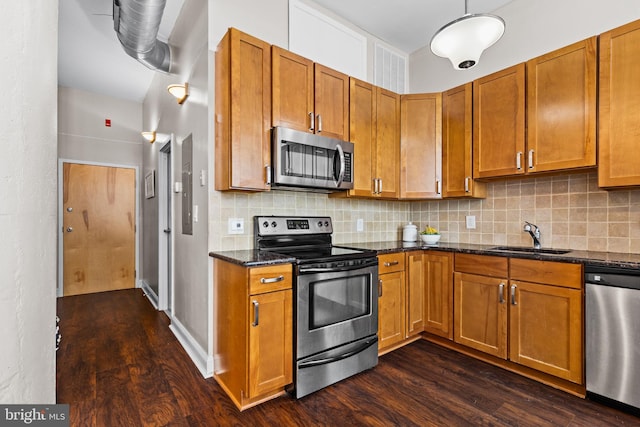 kitchen with tasteful backsplash, a sink, brown cabinets, stainless steel appliances, and dark wood-style flooring