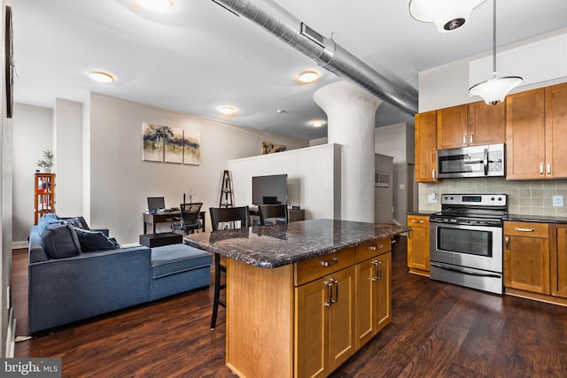 kitchen with a kitchen bar, appliances with stainless steel finishes, open floor plan, and decorative backsplash