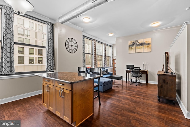 kitchen with a center island, brown cabinets, a breakfast bar, and dark wood-style flooring