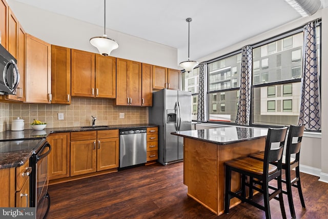 kitchen featuring a kitchen breakfast bar, tasteful backsplash, stainless steel appliances, brown cabinetry, and dark wood-style flooring