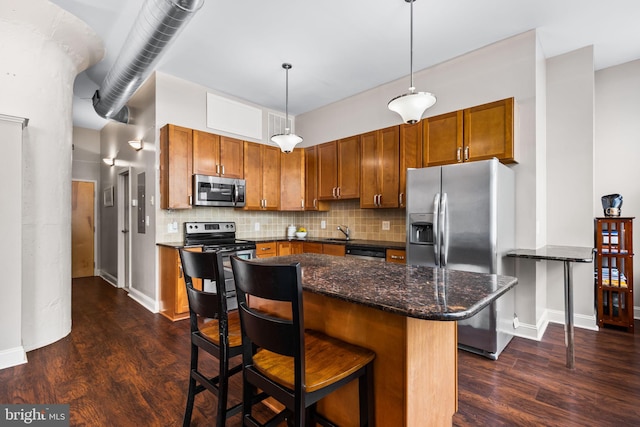 kitchen with brown cabinets, tasteful backsplash, dark wood-style flooring, and stainless steel appliances