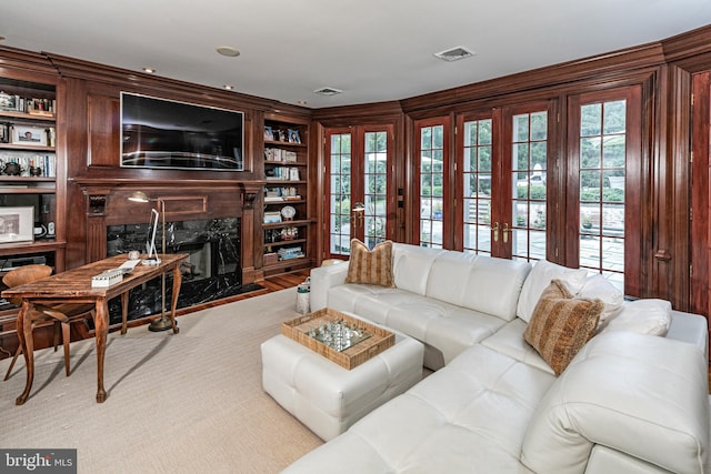 living area featuring built in shelves, french doors, visible vents, and a fireplace