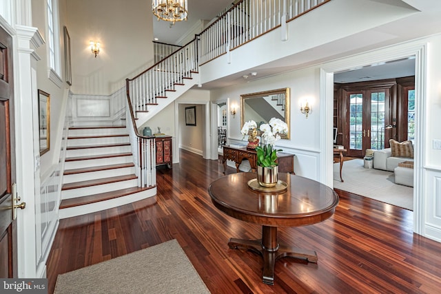 entrance foyer with french doors, a notable chandelier, dark wood finished floors, and stairs