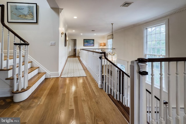 hallway featuring recessed lighting, visible vents, ornamental molding, light wood-type flooring, and baseboards