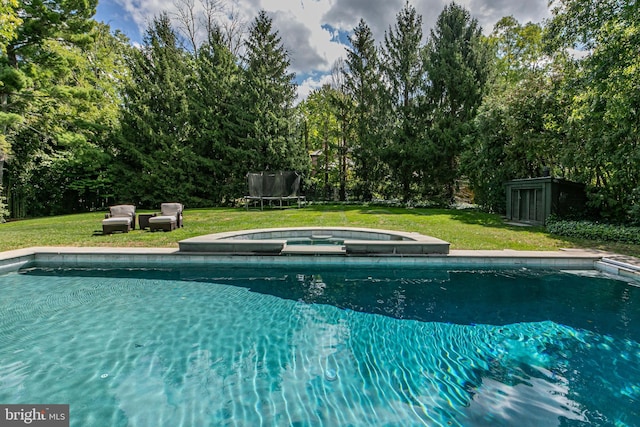 view of pool with a pool with connected hot tub, a trampoline, and a yard