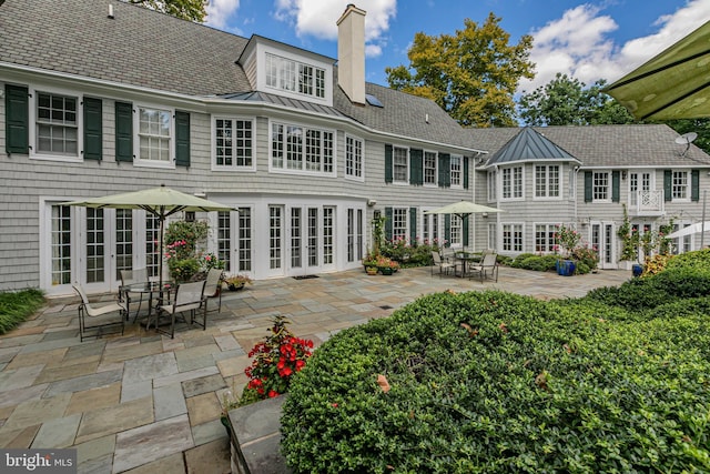 rear view of house featuring a standing seam roof, a patio, french doors, and a chimney